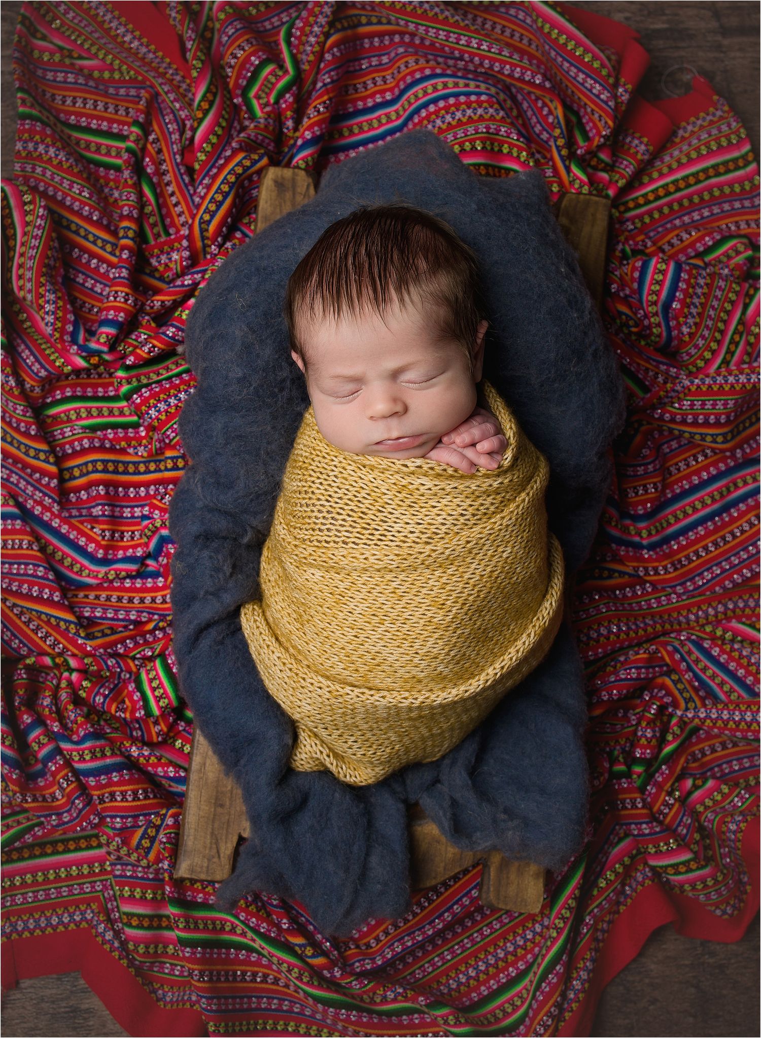 Colorful Newborn Photo by Valerie Kay Photography newborn swaddled in gold posed over cultural fabric