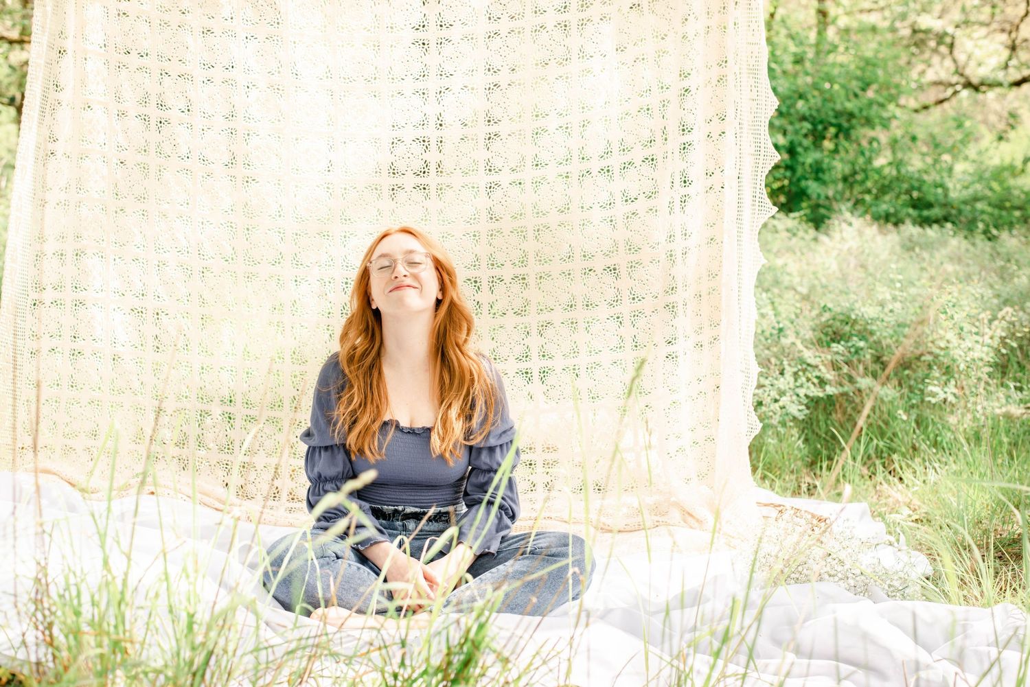 Natural outdoor photography series with model seated on stool against textured backdrop.