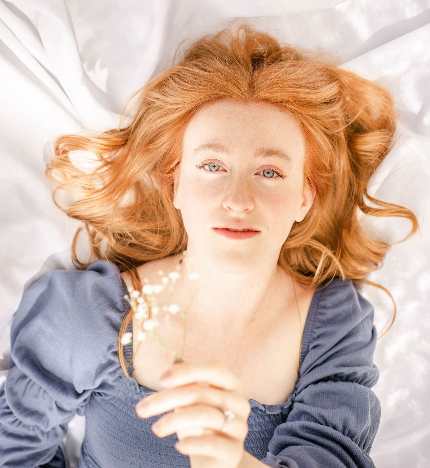 Ethereal portrait series with blue top against white bedding with dreamy lighting.