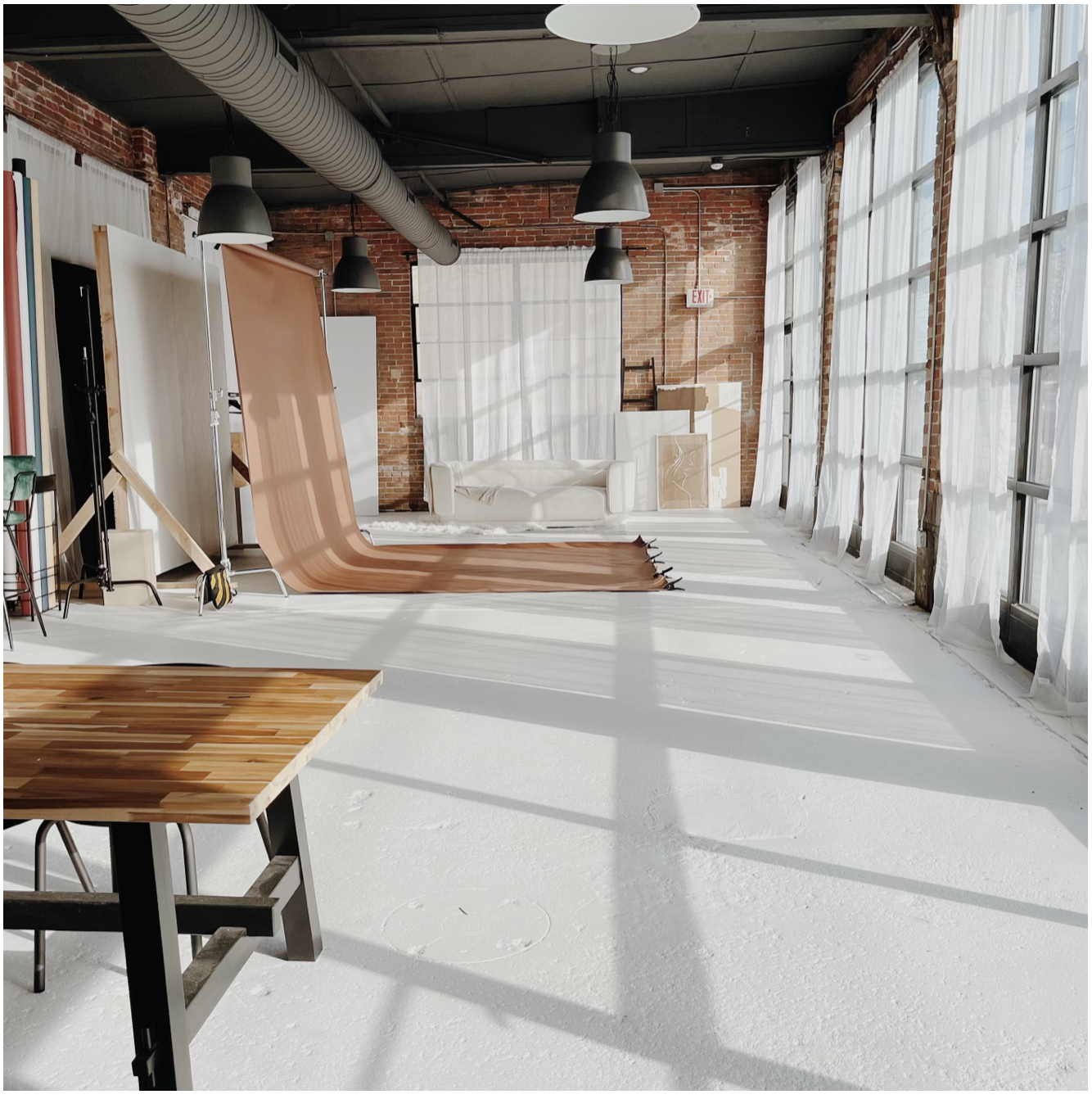 Modern industrial photo studio space with white backdrop and natural lighting.