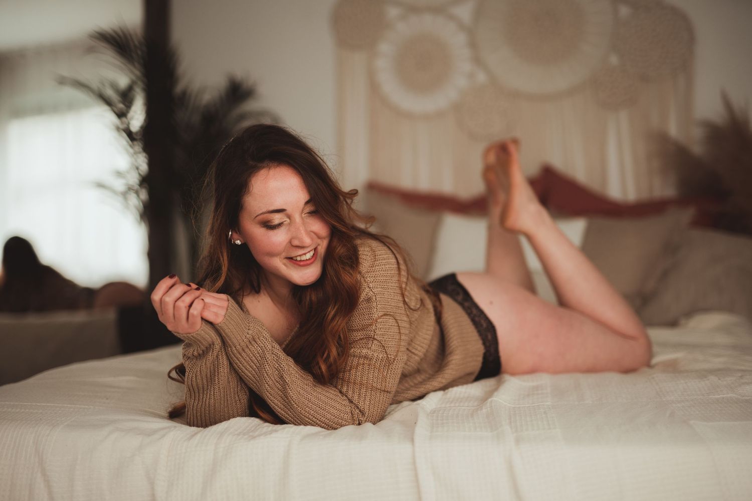 Femme brune allongée sur un lit lors d'une séance boudoir à Baudour près de Mons en Belgique