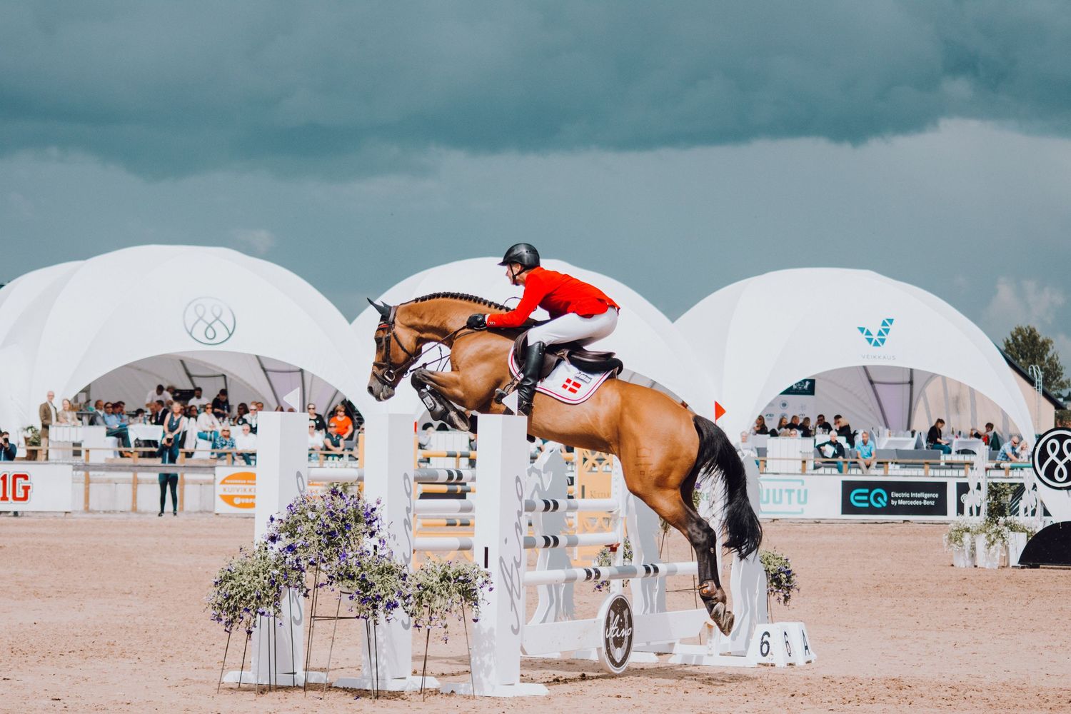 A horse and rider clearing a high jump during an equestrian competition.