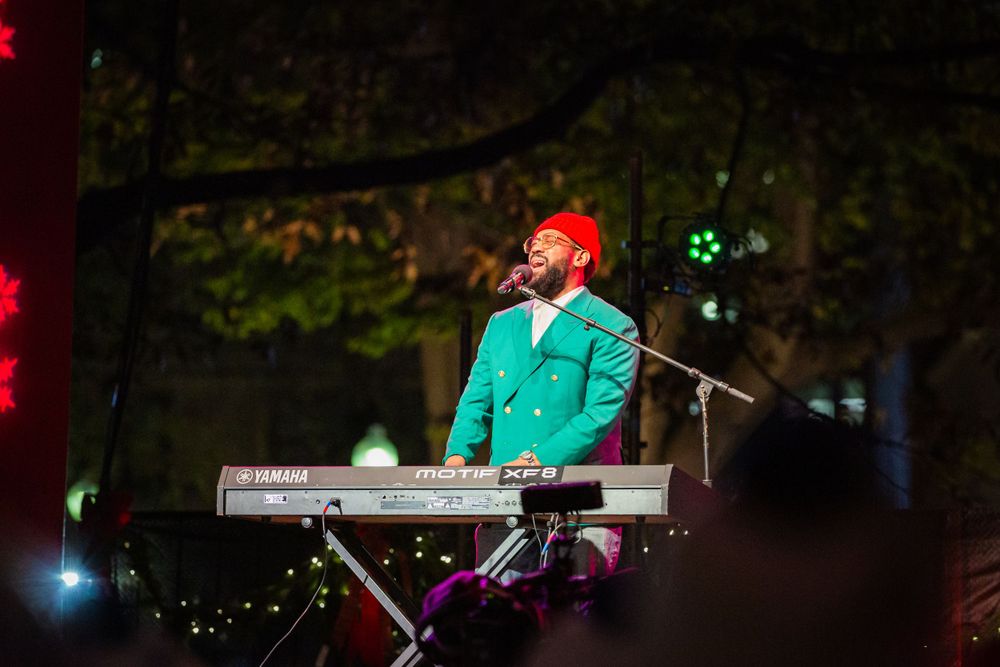 PJ Morton plays the keyboard and sings on stage at a Christmas tree lighting event in the Boston Commons