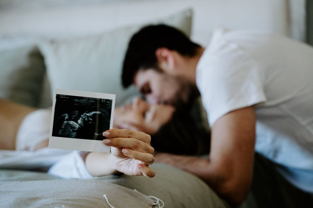 A series of ultrasound photos being held and shared in an intimate indoor setting.