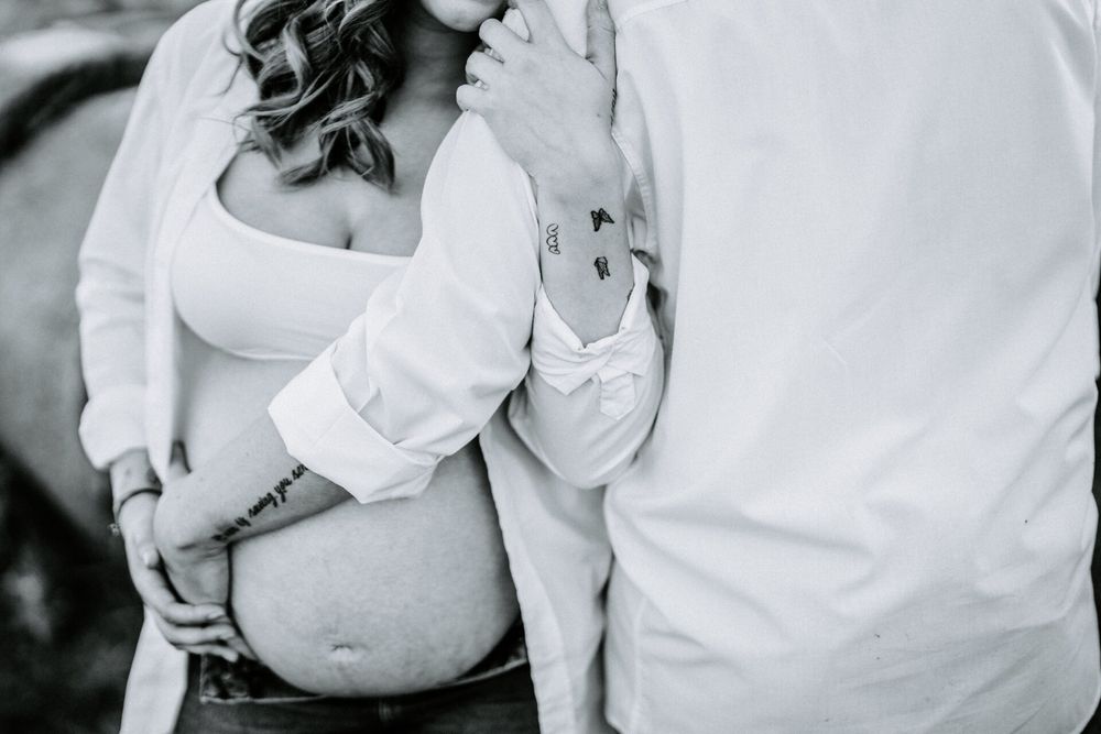 Maternity photo series showing couple embracing in white clothing.