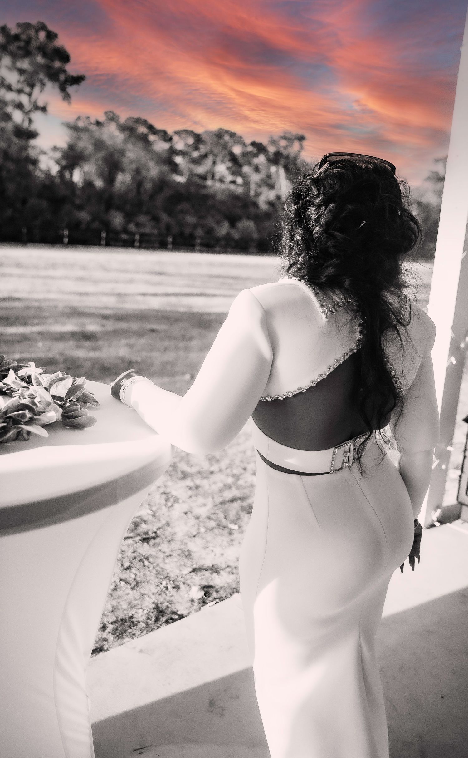 A backlit bridal portrait at sunset with dramatic pink and orange sky.