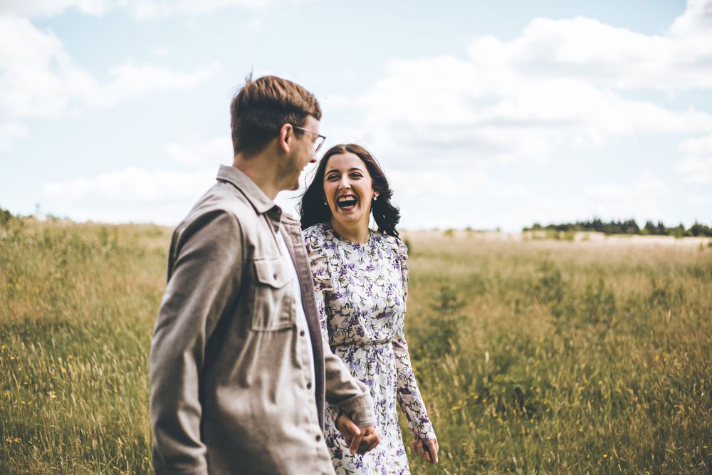 A couple sharing a joyful moment together in a sunny meadow field.