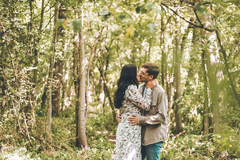 A couple embracing in a sunlit forest setting.
