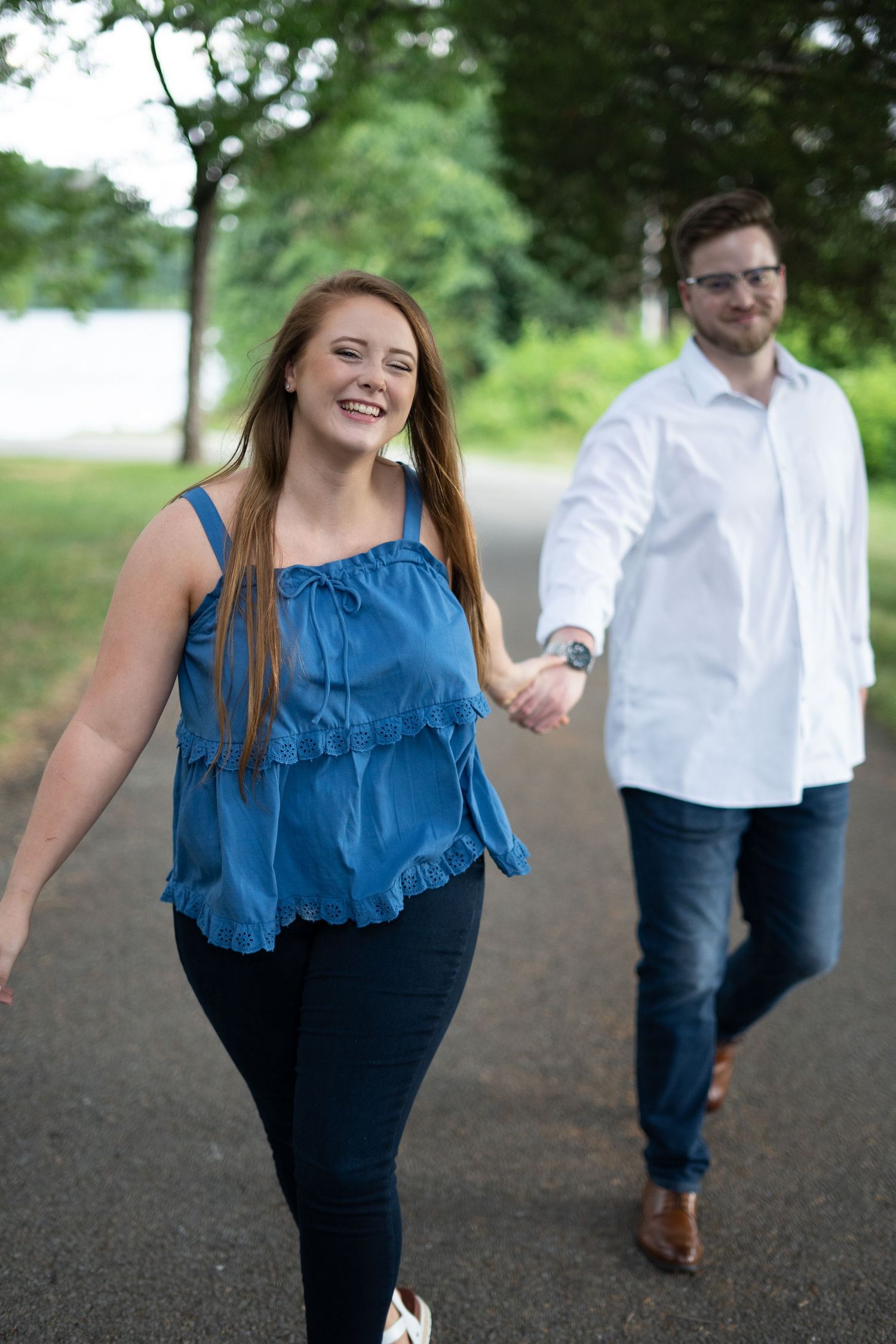 A couple takes a romantic stroll along a tree-lined path on a summer day.