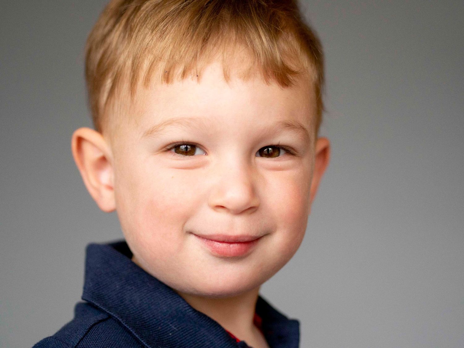 Pre-school aged boy, solid grey background.