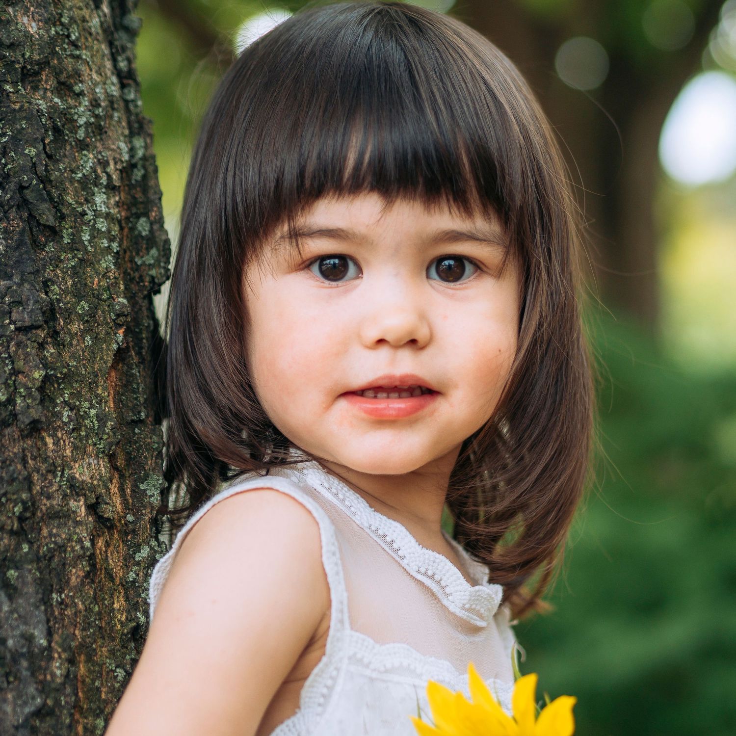 Pre-school aged girl, outdoor background, learning on a tree