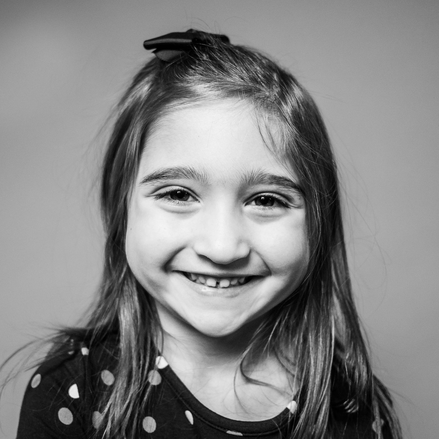 Pre-school aged girl, solid grey background, black and white photo