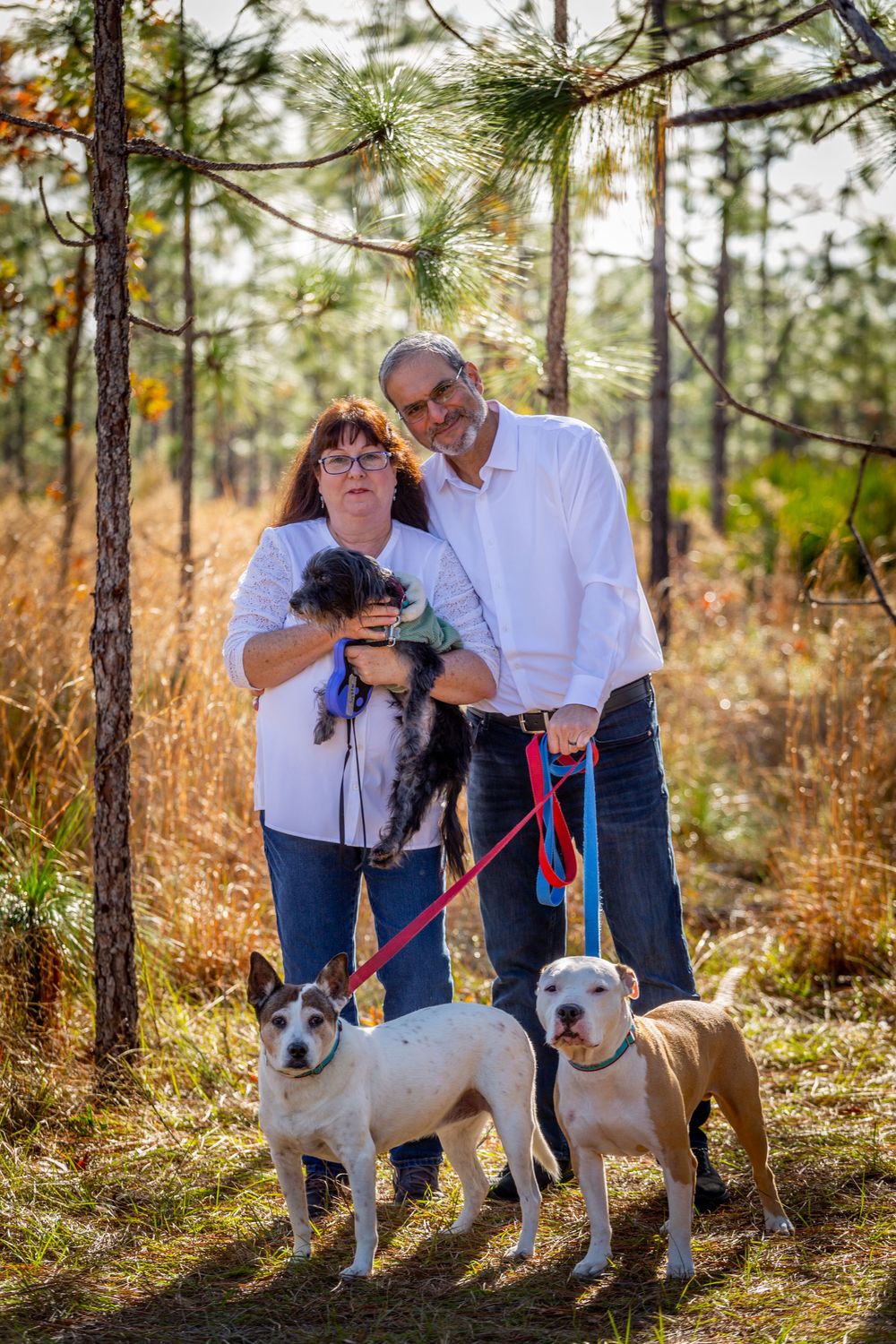 A Husband and Wife, standing together with their dogs.