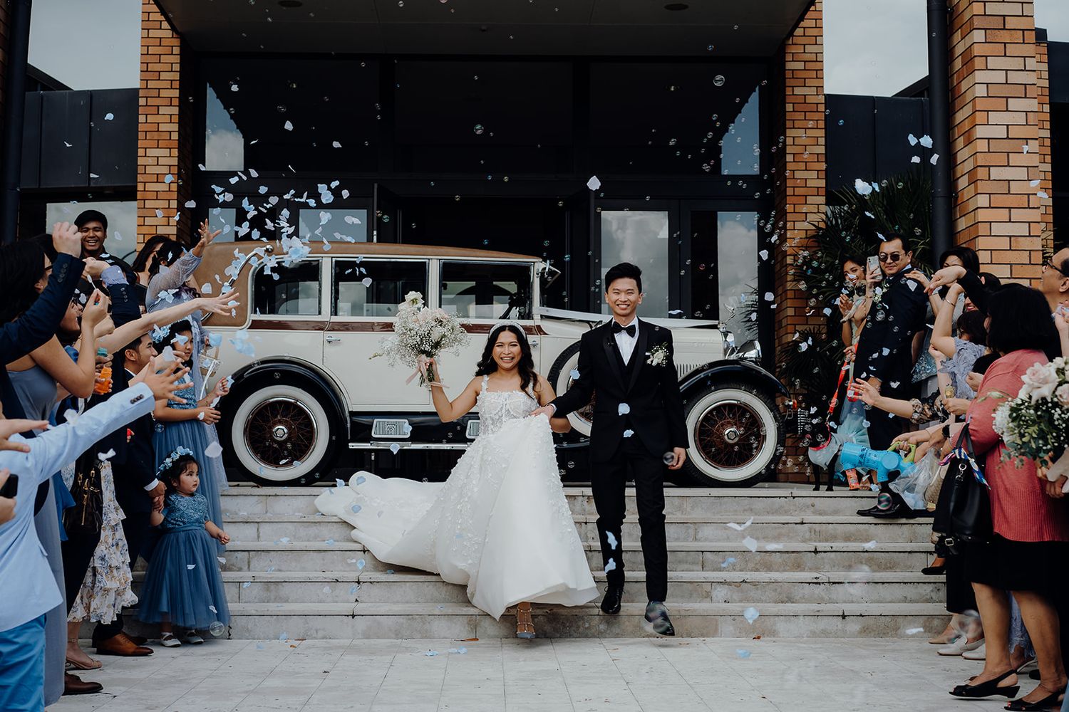 Bride and groom walking down aisle while guests throw confetti