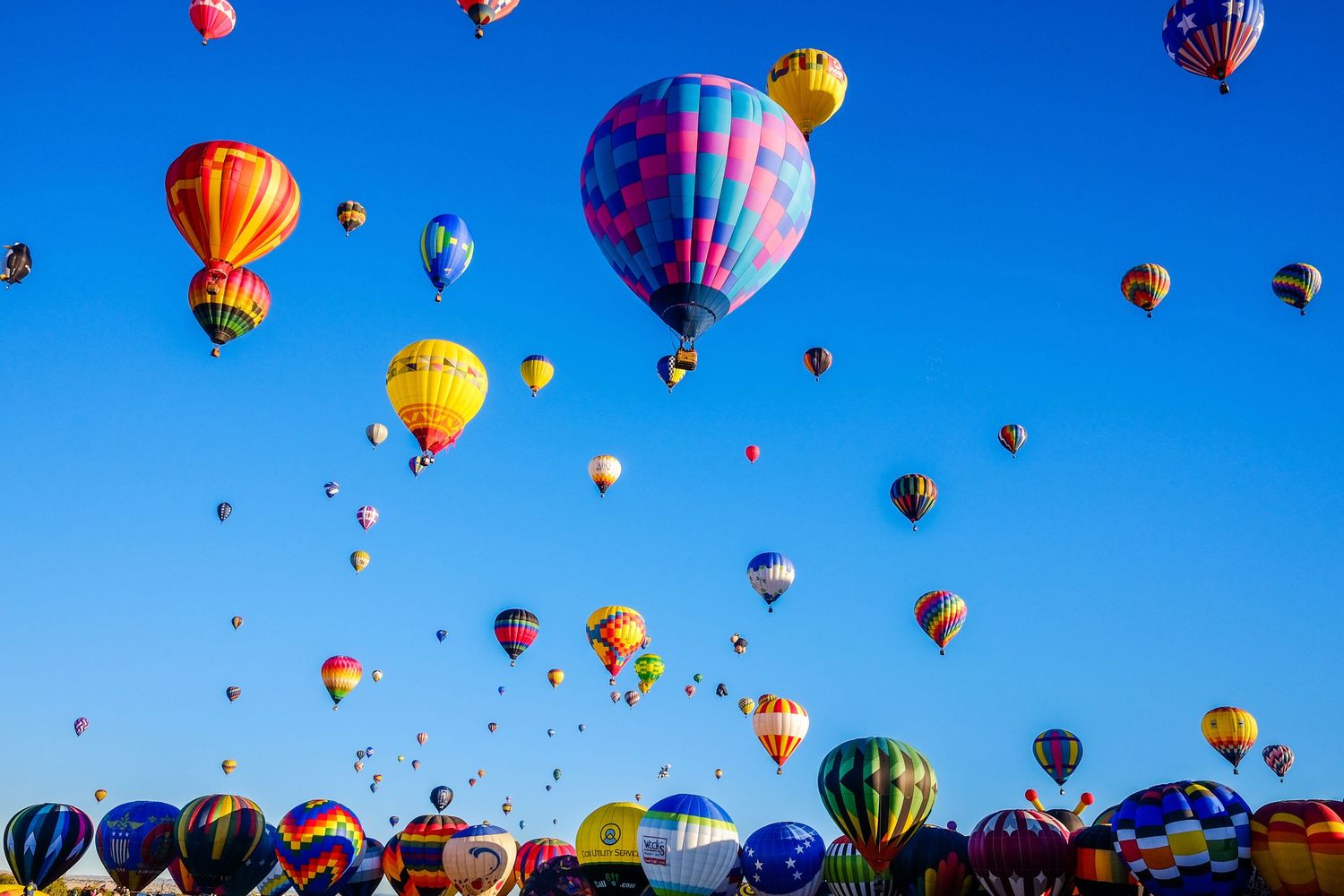 ABQ Hot Air Balloon Fiesta in New Mexico with a blue sky filled with hot air balloons. Image by Alex Kent