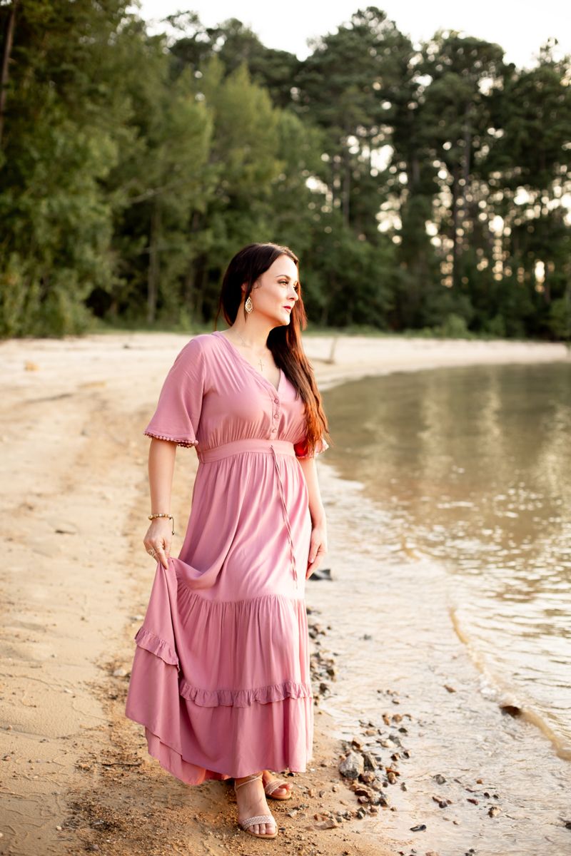 Woman in dusty pink dress standing on the shore of Clarks Hill Lake, SC, looking over the water.