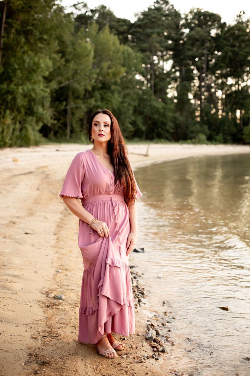 Woman in dusty pink dress standing on the shore of Clarks Hill Lake, SC looking off camera.