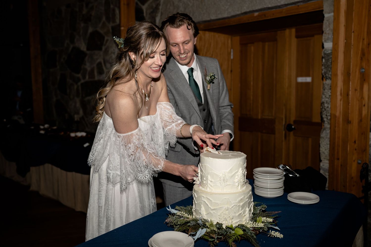 Wedding couple cutting their elegant white tiered cake together at the reception.