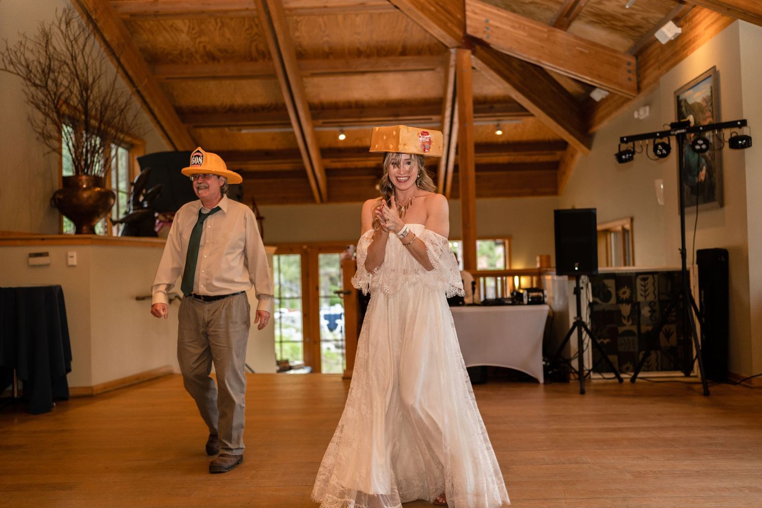 Wedding reception dance floor with rustic wood beams and lighting.