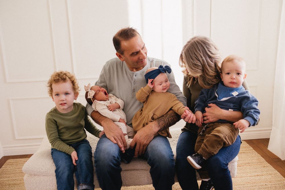 Candid family moments captured on a white couch in natural indoor lighting.