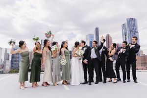 Wedding party lined up against urban skyline backdrop in coordinated formal attire.