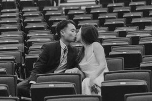 Romantic moments captured in empty auditorium seating area.