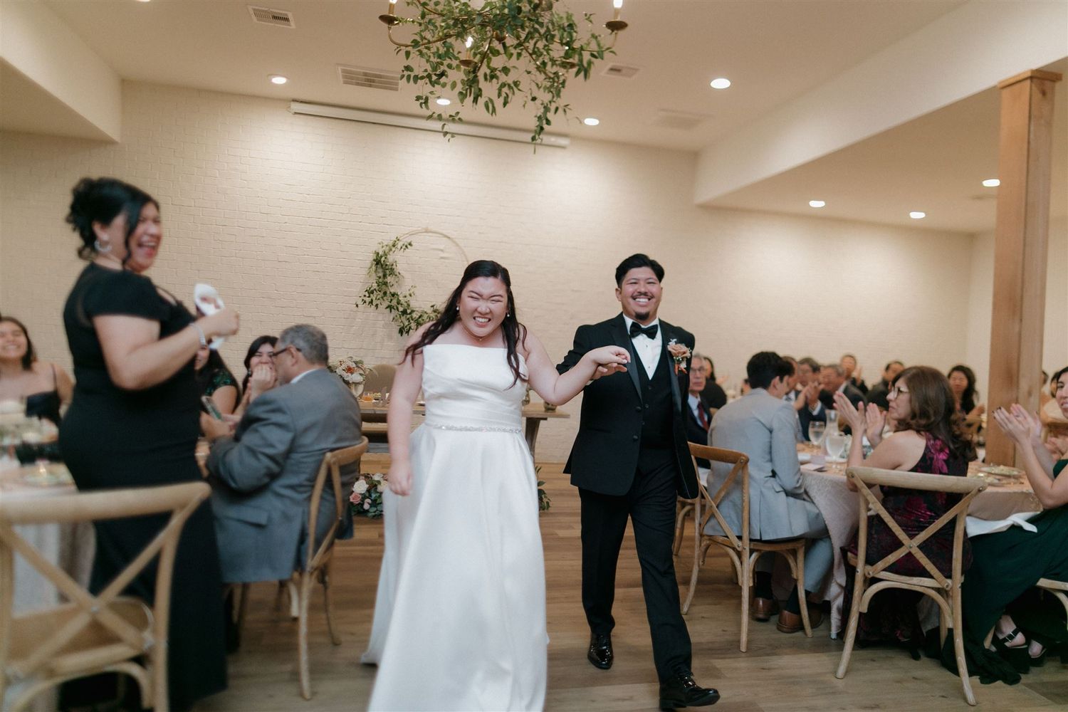 Wedding reception celebration in modern white venue with wooden accents.