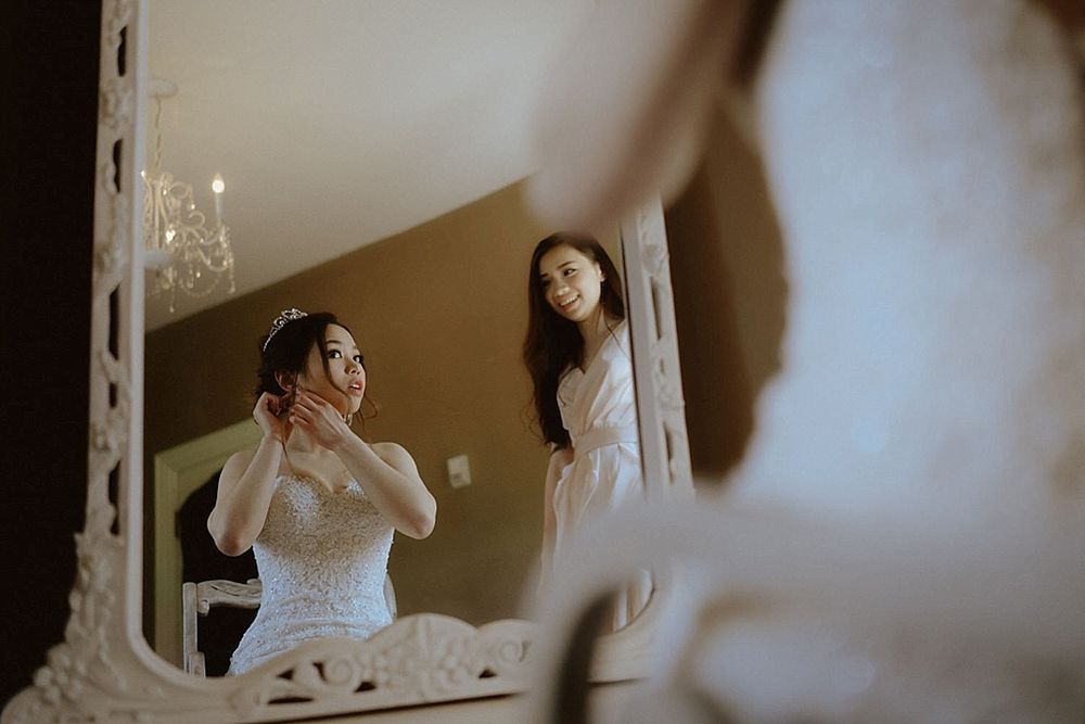 Intimate getting ready moment captured through mirror reflection in bridal suite.