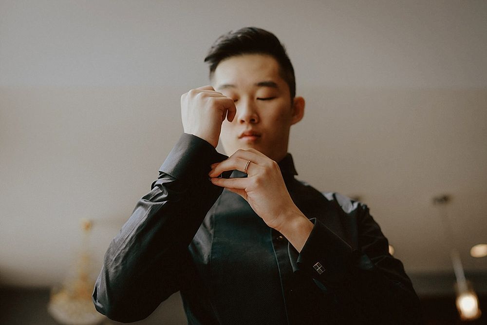 Contemplative moment during wedding preparations in moody lighting.