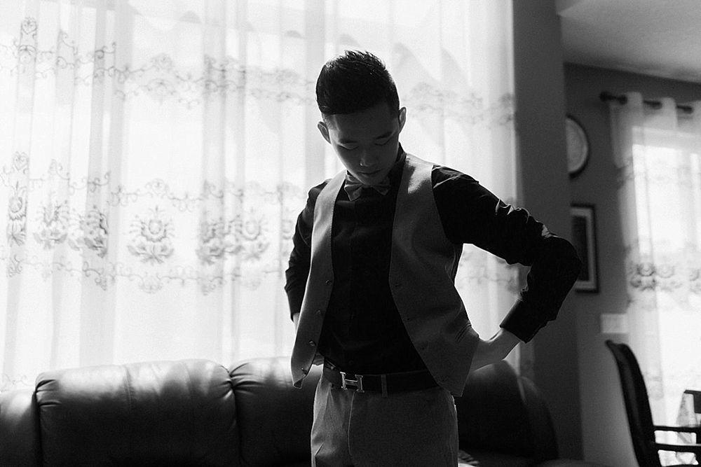 Black and white photo of wedding preparations in an indoor setting with filtered light.