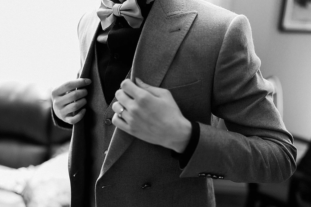 Classic black and white wedding moment captured through curtained windows.