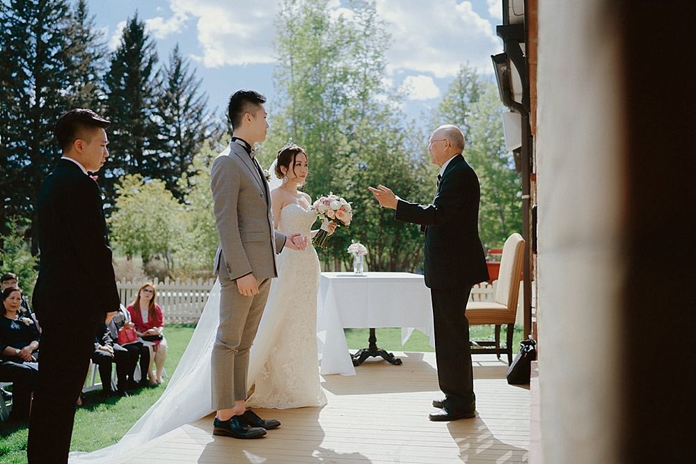 Wedding ceremony taking place under a covered outdoor venue with natural lighting.