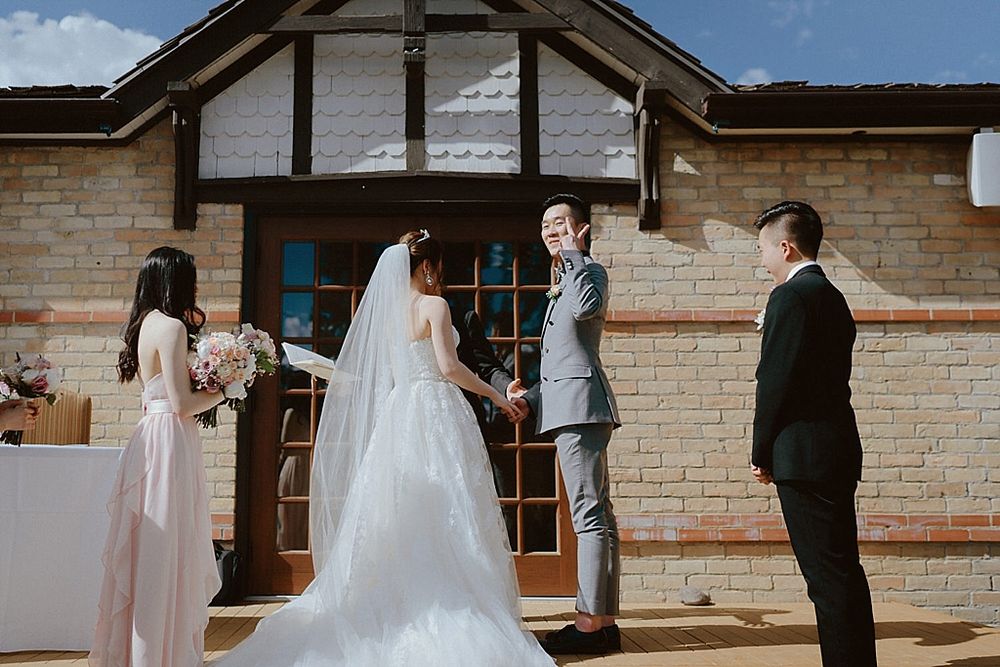 Wedding ceremony at a brick Tudor-style venue with outdoor seating.