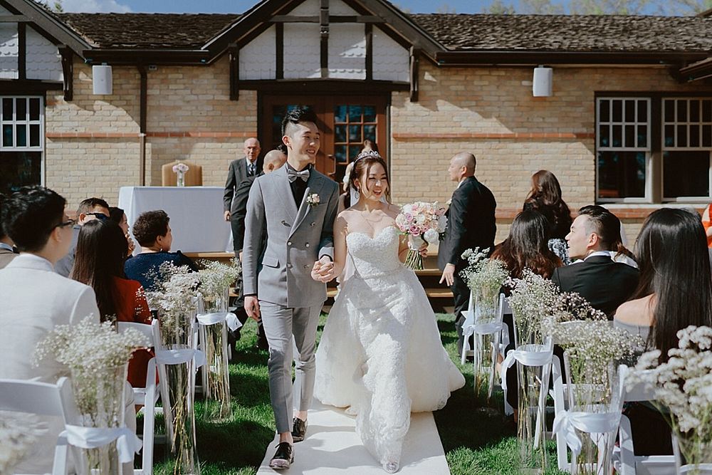 Garden wedding reception setup with white chairs and rustic Tudor architecture.