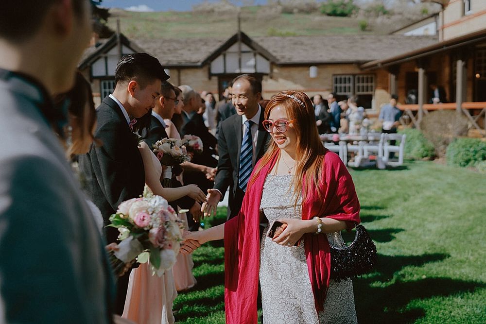 Wedding guests gathered outside a Tudor-style building for outdoor celebration.