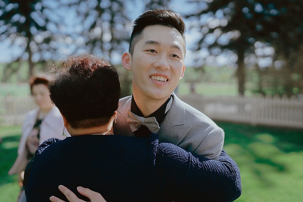Emotional embraces shared during outdoor wedding reception with lush greenery backdrop.