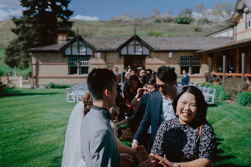 Wedding celebration at a scenic outdoor venue with Tudor-style buildings and green lawns.