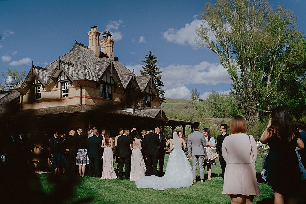 Scenic outdoor wedding ceremony venue with Tudor-style architecture under blue skies.