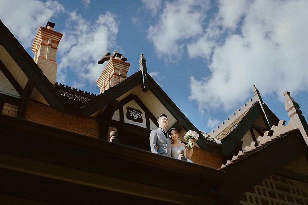 Architectural detail of Tudor building roofline with multiple chimneys against blue sky.