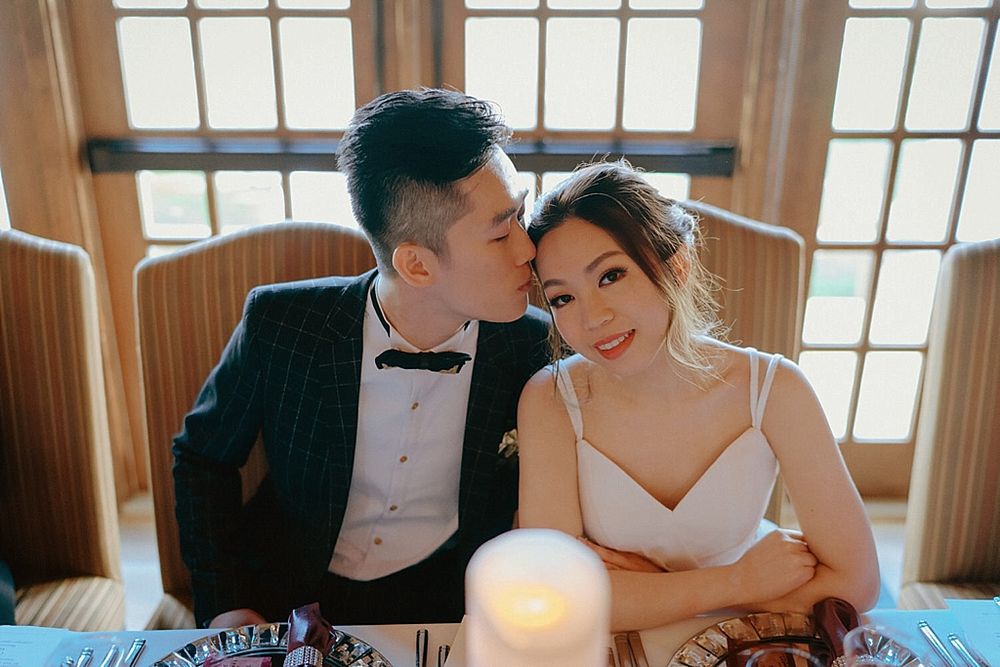 Intimate moment between couple at wedding reception with candlelight on table.