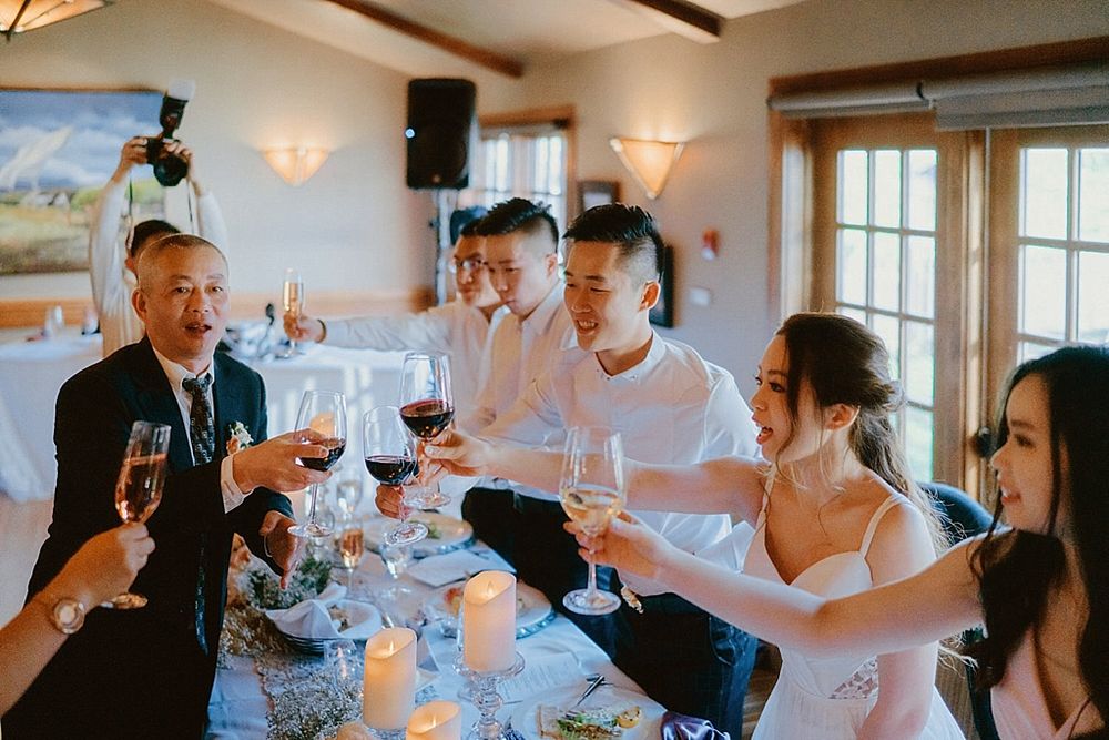 Wedding guests toasting and celebrating at reception dinner table.