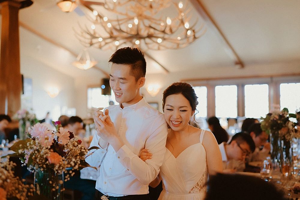 Joyful celebration moment during wedding reception under elegant chandelier lighting.