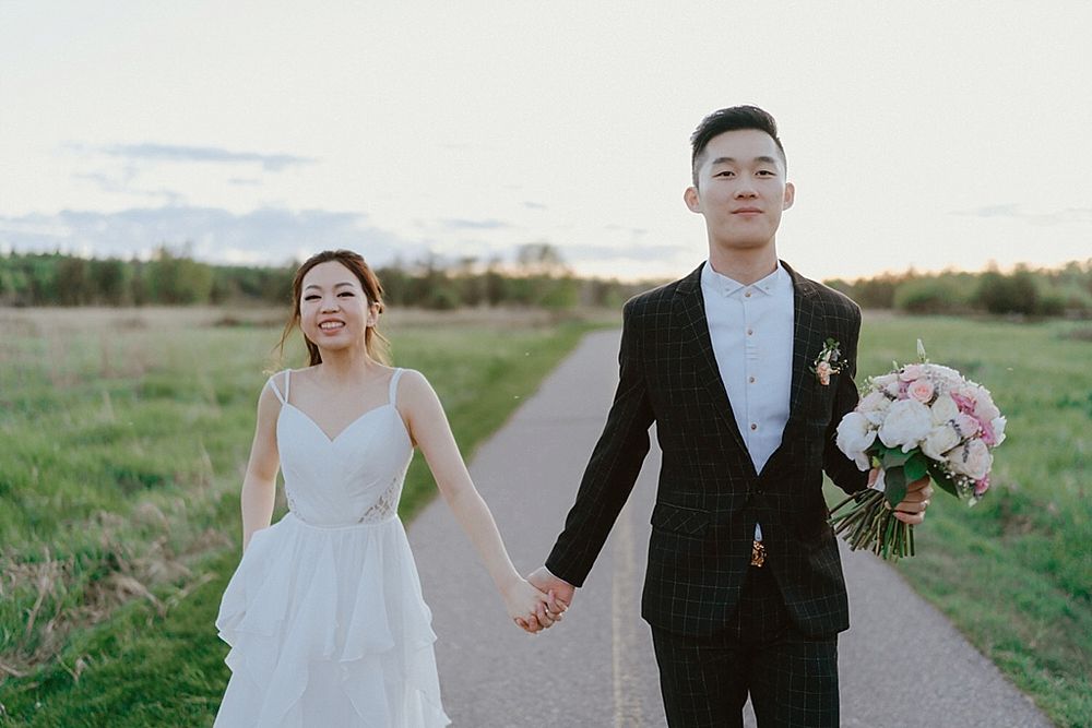 Joyful wedding couple shares intimate moments along a countryside path.