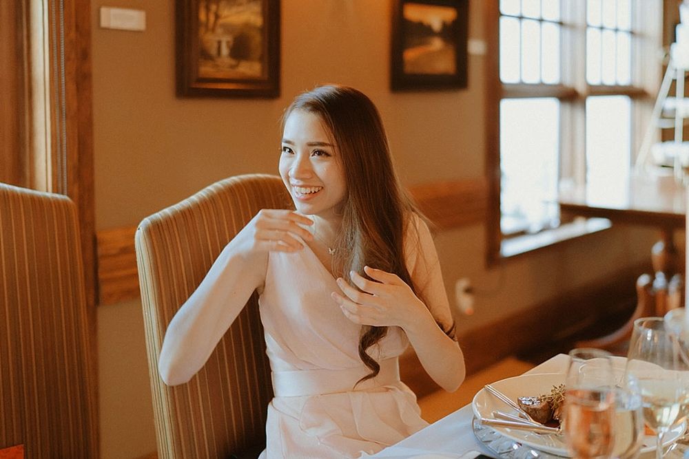 A person in formal attire sits at an elegantly set dinner table during a wedding reception.