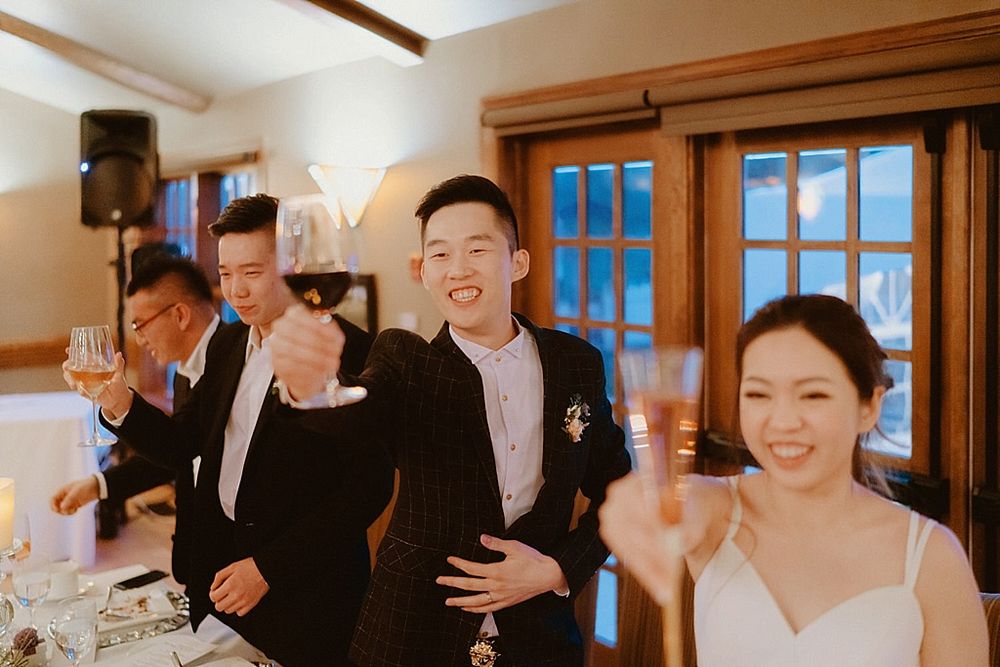 Wedding guests laughing and celebrating during a reception dinner in a rustic venue.