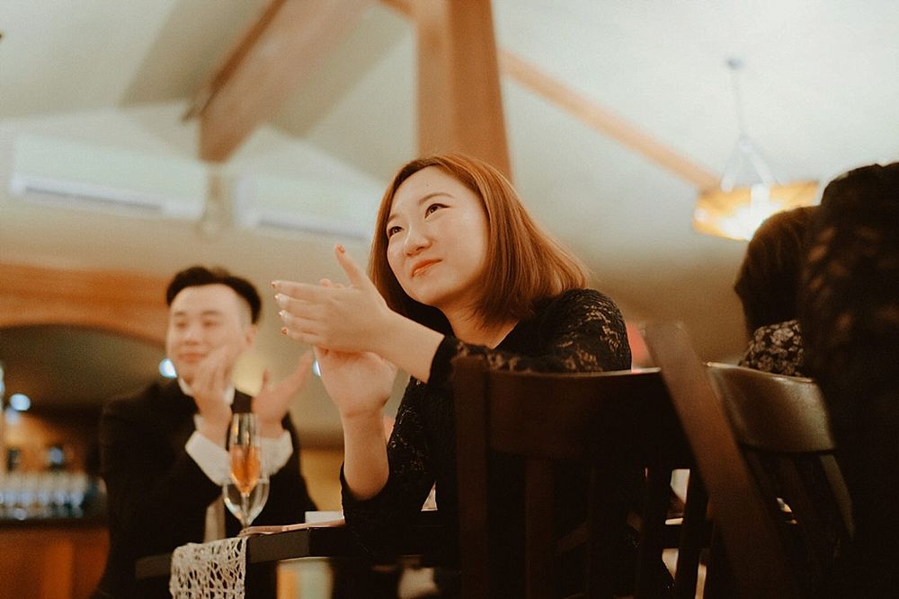 Reception guests applaud during celebrations in a warmly lit venue.
