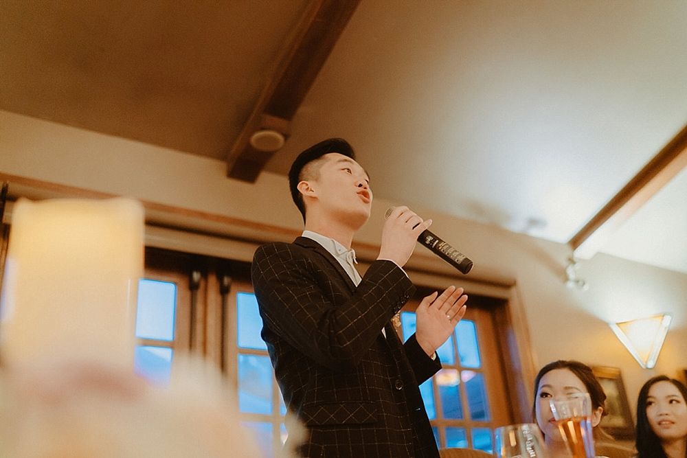 Wedding reception guests dancing together in a warmly lit venue with antler chandeliers overhead.