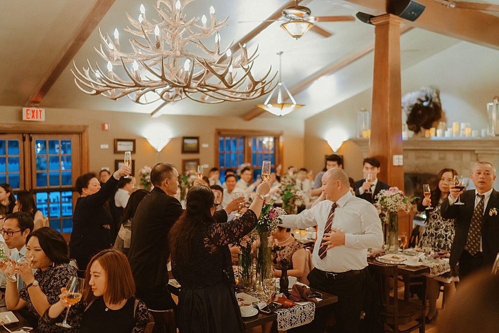 Wedding party celebrating under antler chandeliers in a rustic reception hall.
