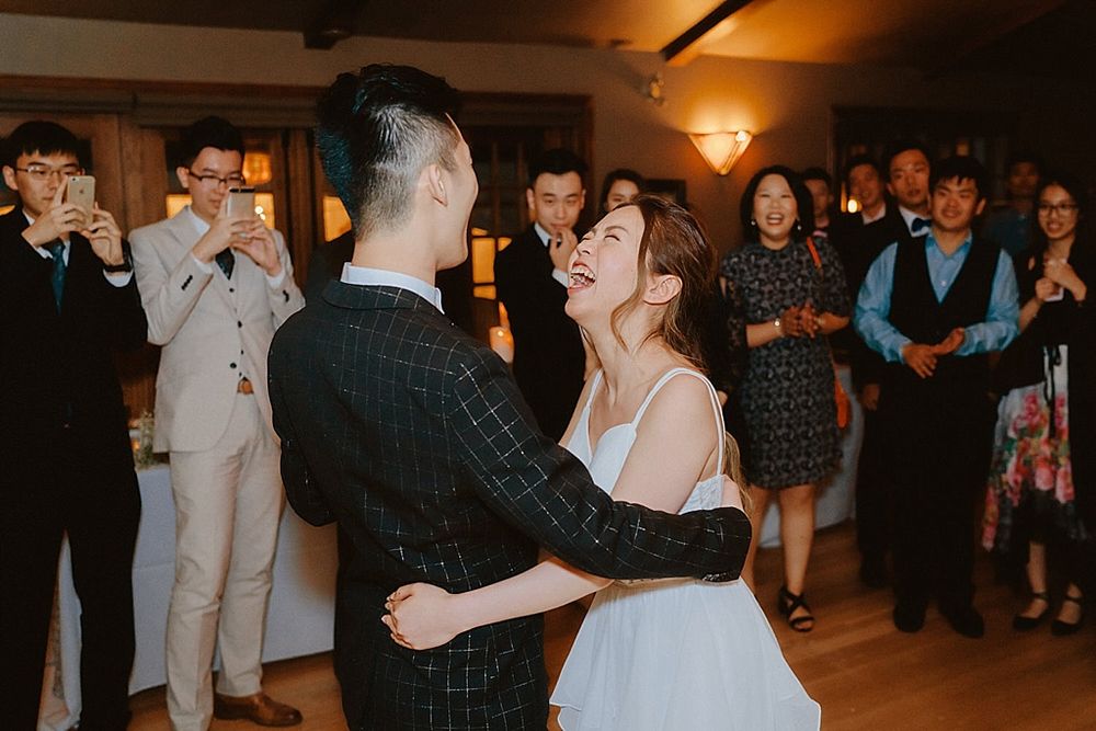 Wedding celebration with guests dancing in a rustic venue with warm lighting.