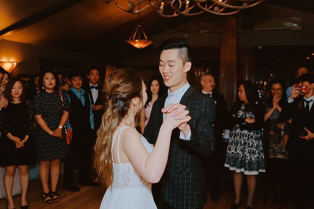 Wedding reception with dancing guests in a warmly lit venue with rustic decor.